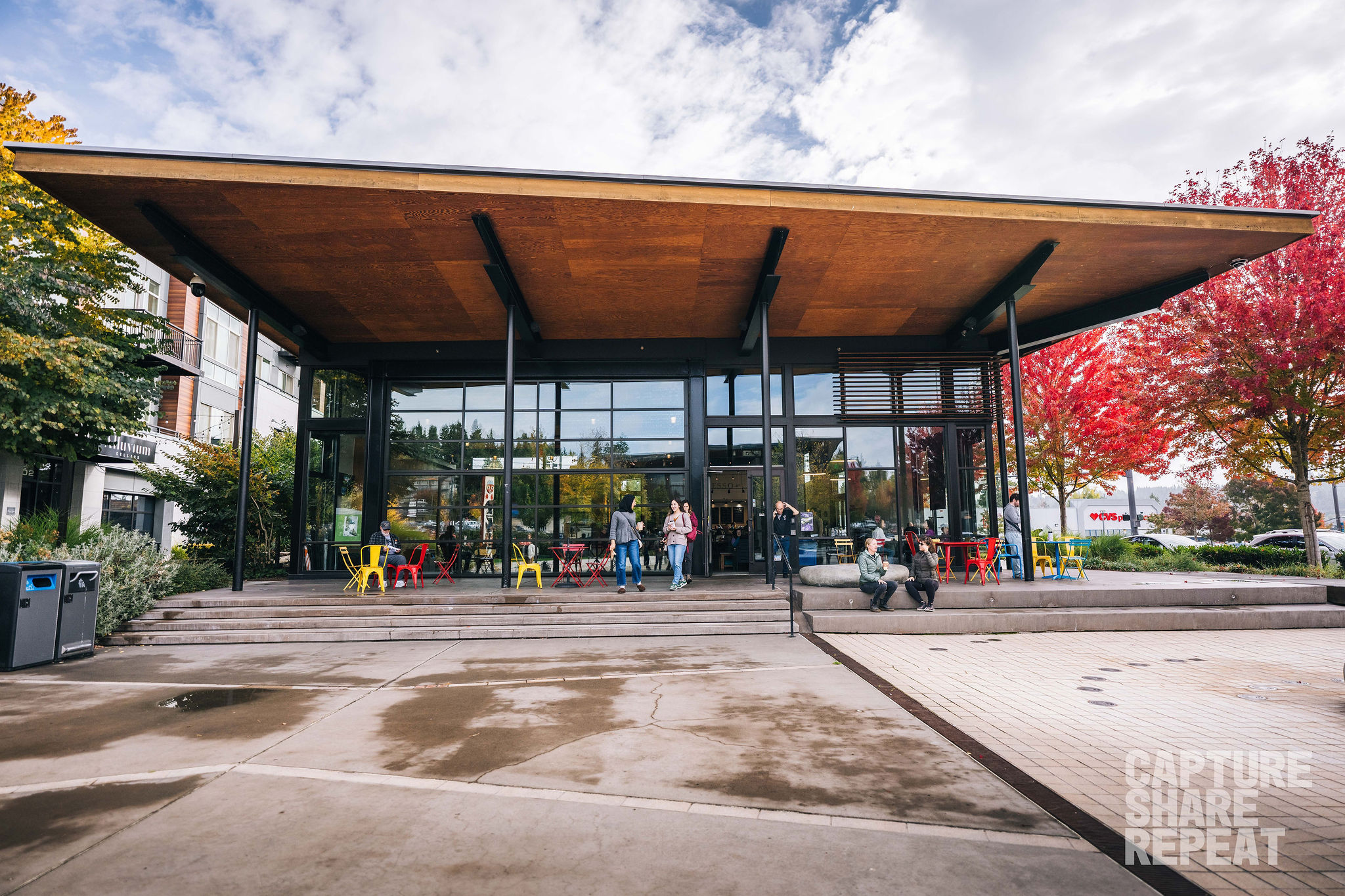 Open courtyard with a large building with windows and large awning with trees surrounding the building.